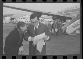 Fotografia "Colunista Ricardo Amaral, no Galeão onde exibe o contrato assinado pelo cantor Ray Charles; fot. 2 - O colunista Ricardo Amaral, exibindo o contrado [contrato] assinado por Ray Charles, ao transitar, ontem, pelo Galeão, com destino à São Paulo, Reportagem de Setorista" ([Local n/d] , 1963) [negativo]. / Fotógrafo(a): Fonseca.  -- ITEM-0002.