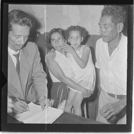 Fotografia "17º D.P. tarado e suas vítimas. (E.M.S. menor que foi estrupada pelo marginal Manoel de Oliveira vulgo Pé de Boi, na favela do Parque da Alegria em dezembro de 62, Reportagem de Oscar Cardoso" ([Local n/d] , 1963) [negativo]. / Fotógrafo(a): Paulo André.  -- ITEM-0011.