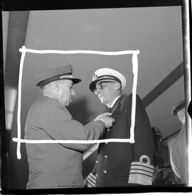 Fotografia "BRASÍLIA - Ministro da Marinha entrega condecorações (medalha do Mérito Naval) à diversas personalidades (Helio de Almeida pelo ministro Silvio Mota) e outros personagens; MEDALHA DO MÉRITO BSB" ([Local n/d] , 1963) [negativo]. / Fotógrafo(a): Neville.  -- ITEM-0009.