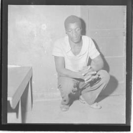 Fotografia "17º D.P. tarado e suas vítimas. (E.M.S. menor que foi estrupada pelo marginal Manoel de Oliveira vulgo Pé de Boi, na favela do Parque da Alegria em dezembro de 62, Reportagem de Oscar Cardoso" ([Local n/d] , 1963) [negativo]. / Fotógrafo(a): Paulo André.  -- ITEM-0010.