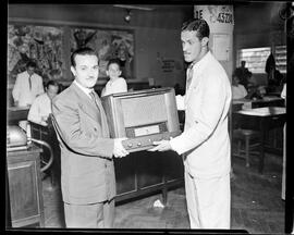 Fotografia "Entrega de prêmio na redação - aparecem Ademir, Zezé e o menino premiado" ([Local n/d] , [Data n/d]) [negativo]. / Fotógrafo(a): Nilo.  -- ITEM-0002.