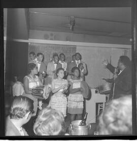 Fotografia "RONDA DAS BUATES [BOITES]; 'RONDA DAS BOITES' ' BOITE AU BON GOUUMET [GOURMET]' 'Ronda das Buartes [Boates]' (Apresentação de Monsueto e suas pastoras), Reportagem de Eli" ([Local n/d] , 1963) [negativo]. / Fotógrafo(a): Roberto.  -- ITEM-0002.