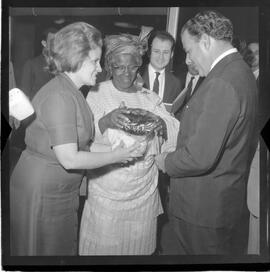 Fotografia "Jango c/ Dª Romana [Brasília]; Visita de D. Romana ao Presidente Jango em Brasília que lhe faz entrega do chapéu típico da Nigéria, Reportagem de Sucursal" ([Local n/d] , 1963) [negativo]. / Fotógrafo(a): Sucursal; Novelli.  -- ITEM-0003.